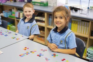 Two Kindergarten children smiling using counters